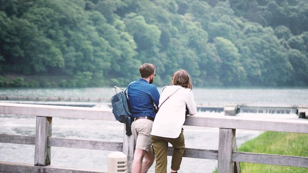 Couple casual traveller man and woman standing on a romantic old wood Arashiyama bridge in Kyoto Japan.