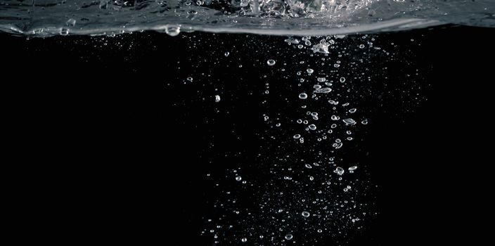 Soda water bubbles splashing and floating drop in black background represent sparkling and refreshing