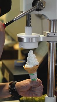 White creamy soft serve ice cream cone made by dairy milk cooling frozen machine for sweet tasty snack.