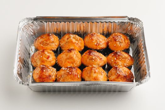 baked sushi rolls in a foil box container