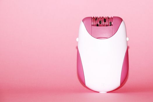 electric handheld epilator on pink background close-up, copy space