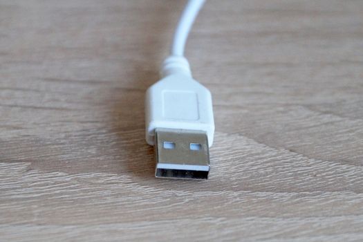 white usb cable on a wooden table close-up