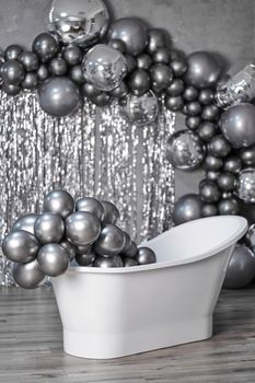 black and white photo white stylish bathtub in empty room with balloons and confetti.