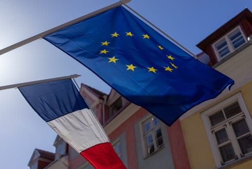 Flags of France and the European Union on the building against the blue sky on a bright Sunny day