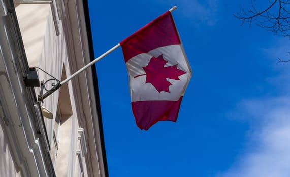 Canada flag on building against blue sky on bright Sunny day