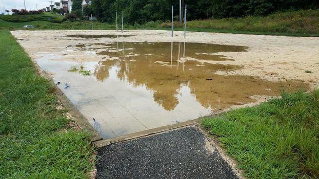 path to sand in volleyball court with large water puddle