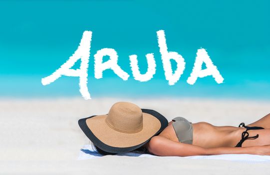 ARUBA title written on sky above beach travel bikini suntan woman sleeping relaxing covering face with hat doing siesta. ARUBA text in blue ocean copyspace above. Summer and sun vacation holidays.