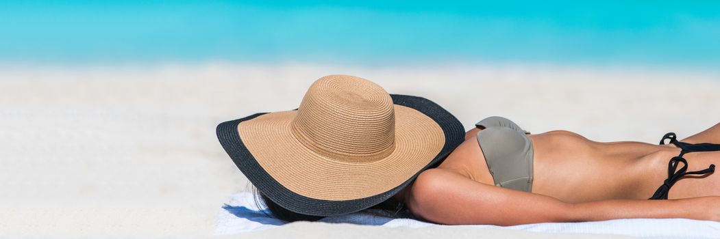 Beach relaxation woman sleeping with hat banner sun tanning covering her face with sunhat for uv solar protection on blue ocean background. Vacation girl relaxing resting on summer travel.
