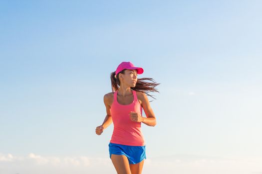 Fitness woman running healthy lifestyle on blue sky background. Empty copyspace.