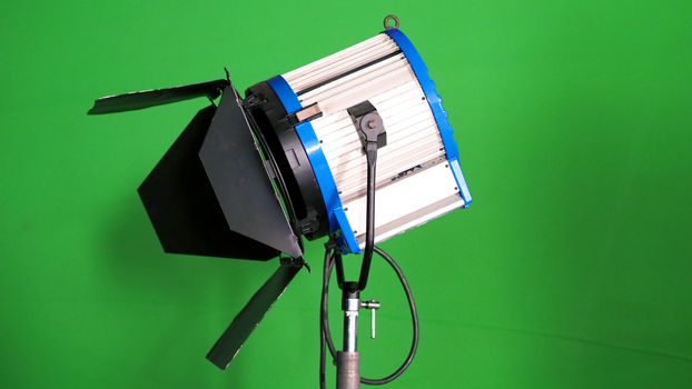 Big studio LED spotlight for video movie or photo film production with green screen background for chroma key technique in post lab process and professional equipment such as tripod and others.