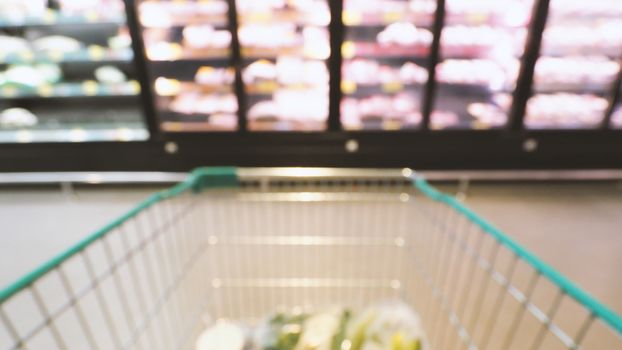 Blurry images of supermarket cart from people POV or point of view angle and shopping in the big hypermarket of Bangkok Thailand.