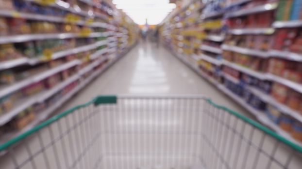 Blurry images of supermarket cart from people POV or point of view angle and shopping in the big hypermarket of Bangkok Thailand.