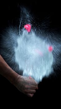 Water balloon exploding or splashing which represent power of refreshing or freshness for viewer and blasted by pencil in hand on black background in the studio.