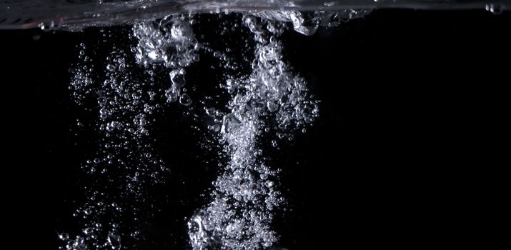 Blurry images of clear transperant soda liquid bubbles splashing or sparkling and moving up in black background for represent the refreshing moments after drink carbonated water.