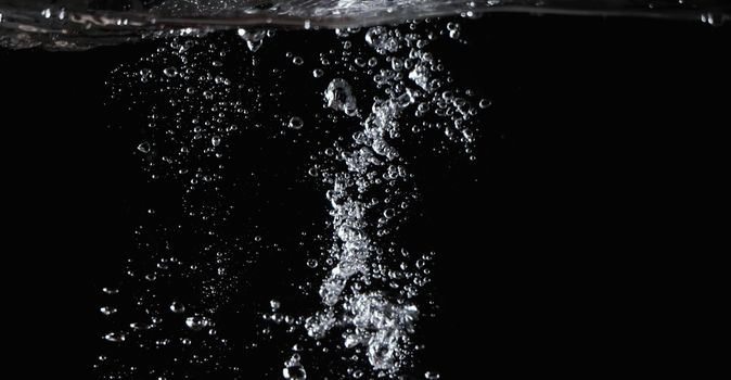 Blurry images of clear transperant soda liquid bubbles splashing or sparkling and moving up in black background for represent the refreshing moments after drink carbonated water.