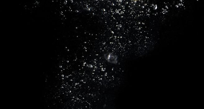 Blurry images of clear transperant soda liquid bubbles splashing or sparkling and moving up in black background for represent the refreshing moments after drink carbonated water.