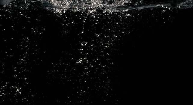 Blurry images of clear transperant soda liquid bubbles splashing or sparkling and moving up in black background for represent the refreshing moments after drink carbonated water.