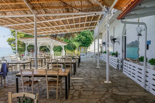 Restaurant outdoor seating area by the sea with a few customers in Kryopigi, Kassandra peninsula.