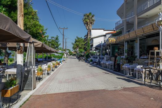 Restaurant personnel next to outdoor seating area without tourists in Hanioti, Kassandra peninsula.