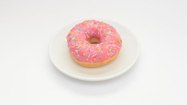 One pink glazed donut on plate on white background.Sweet dessert food for snack. 