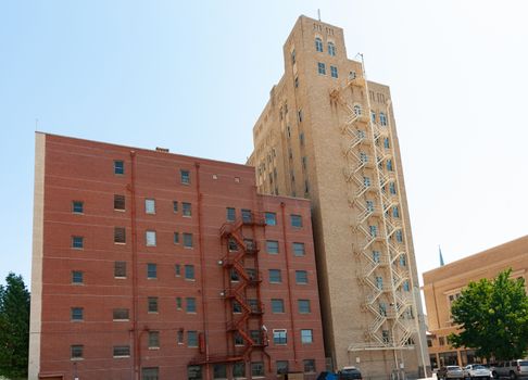 Two apartment buidling standing together of different color brick construction with old-fashioned exterior fire escape stairs and windows.