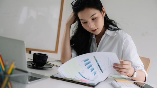 Serious focused businesswoman working with financial marketing report.