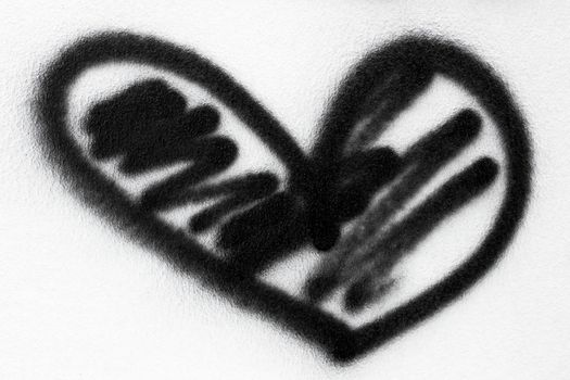 Black heart painted with spray paint on a white wall.