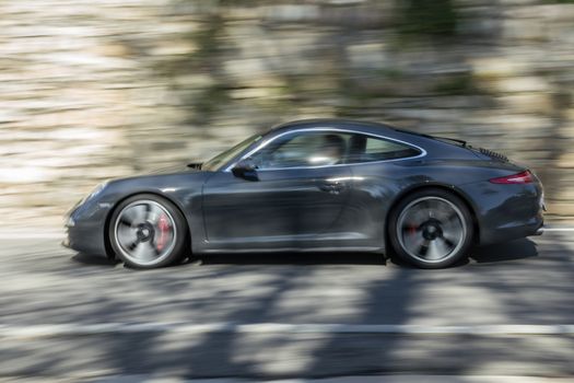 Sports car hurtling in the city, into the wind and the sun.