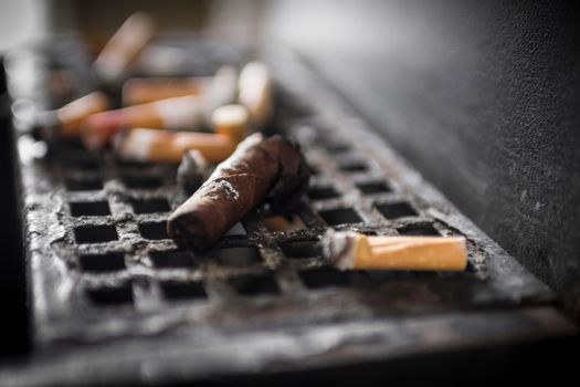 An ashtray full of cigarette butts and a cigar.