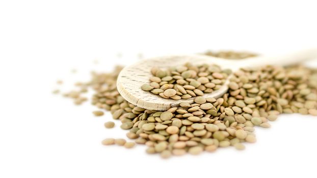 Heap of green lentil isolated on white background with wooden spoon. Shallow DOF.