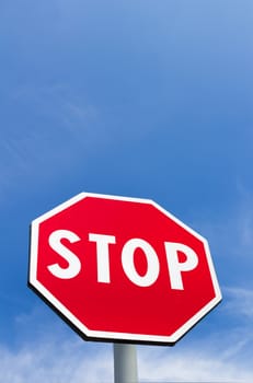 Stop sign isolated on a blue sky background with white clouds. Space for text.