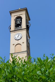 Clock and bell tower of a church in italy. Blue sky. Bottom view.
