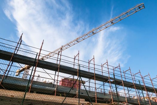 Construction crane and unfinished building on sky background. Bottom view.