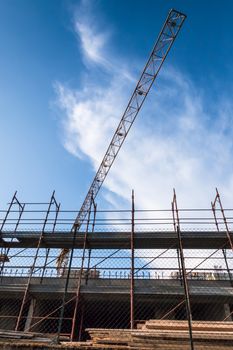 Construction site with crane in a day with blue sky and white clouds. Bottom view.