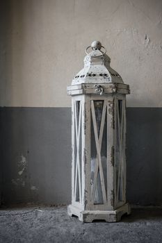 An old lantern in wood painted white, powered by a candle.