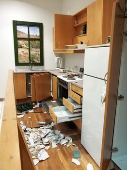 A mess in the kitchen, broken dishes, open cabinets.