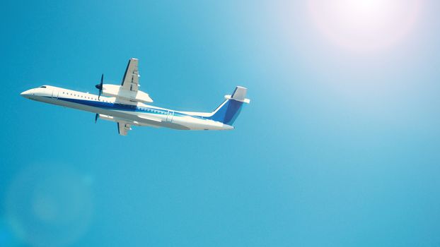 Airplane taking off to the blue sky from international airport runway in Sapporo Hokkaido Japan and have sun light flare to camera and shoot from uprisen or low angle view.