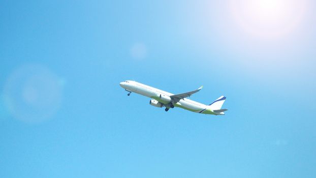 Airplane taking off to the blue sky from international airport runway in Sapporo Hokkaido Japan and have sun light flare to camera and shoot from uprisen or low angle view.