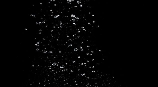 Blurred images of close-up soda water bubbles fizzing up or splashing or sparkling like a exploding of a bomb on black background for represent refreshing from carbonated drinks menu.