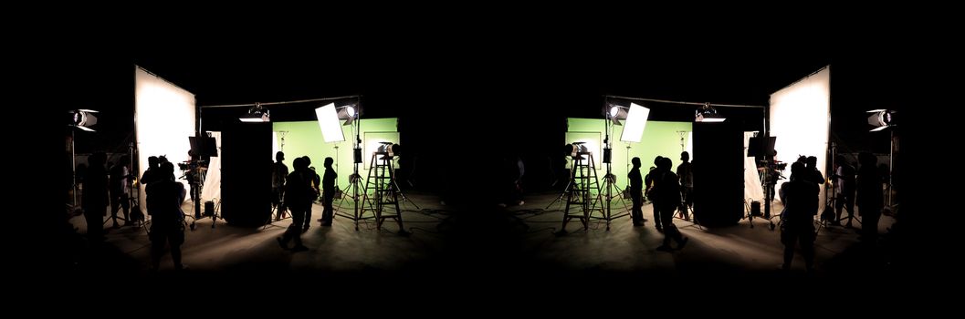 Silhouette images of video production behind the scenes or b-roll or making of TV commercial movie that film crew team lightman and cameraman working together with director in big studio with professional equipments 