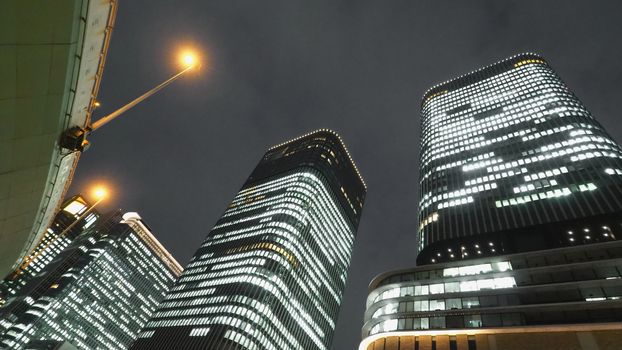 Low or uprisen angle view of modern skyscraper tower building in the night that represent futuristic architecture of office workplace in downtown area of Osaka Japan  