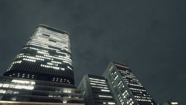 Low or uprisen angle view of modern skyscraper tower building in the night that represent futuristic architecture of office workplace in downtown area of Osaka Japan  