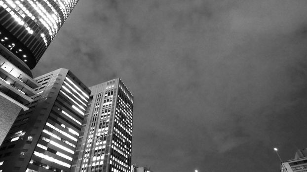 Low or uprisen angle view of modern skyscraper tower building in the night that represent futuristic architecture of office workplace in downtown area of Osaka Japan  