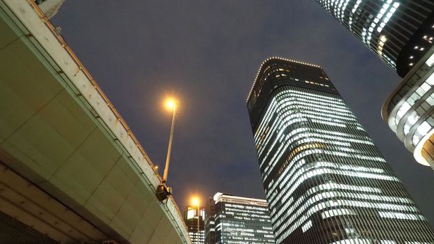 Low or uprisen angle view of modern skyscraper tower building in the night that represent futuristic architecture of office workplace in downtown area of Osaka Japan  