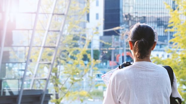 Behind tourist or traveller standing taking a photo of tower in Osaka Japan near station around Umeda area by dslr camera in hands and have a sunset flare in the evening day.