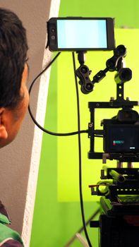 Behind the vdo camera in studio production that shooting or filming green screen background for chroma key technique in post process with professional crew teams and equipments.