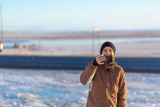Guy tourist walks in winter in Iceland. Takes pictures of nature.