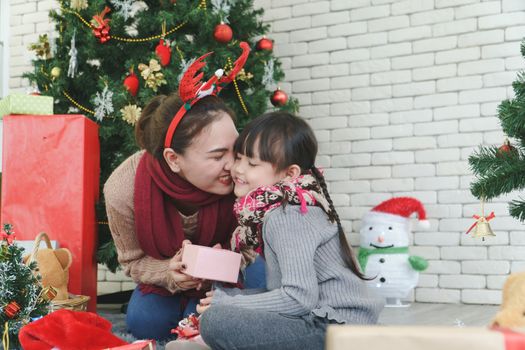 Asian family Happy Christmas and New Year holidays. The mother and daughter prepare to wrap the gift box. And decorate the Christmas tree. The festive season is beginning.