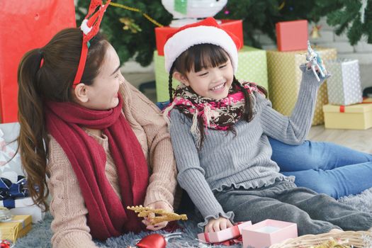 Asian family Happy Christmas and New Year holidays. The mother and daughter prepare to wrap the gift box. And decorate the Christmas tree. The festive season is beginning.