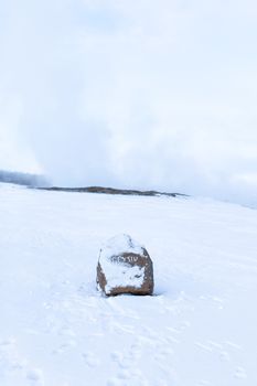 Stone signpost with the inscription geyser covered with snow in winter in iceland.